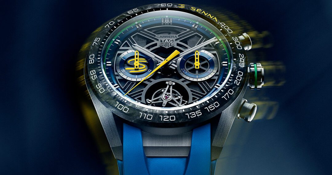 Close-up of a TAG Heuer Carrera Chronograph watch with a complex dial, visible mechanics, and a blue rubber strap on a blurred blue background.