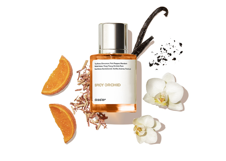 A perfume bottle labeled "Spicy Orchid" sits elegantly amidst orange slices, vanilla pods, and orchid flowers on a white background. This captivating blend is featured in duPont REGISTRY's Fall Shopping Guide as an essential scent for the cooler months.