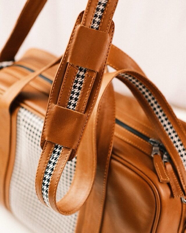 Close-up of a Walter Leather Bespoke brown leather bag, featuring a houndstooth fabric detail and a patterned shoulder strap.