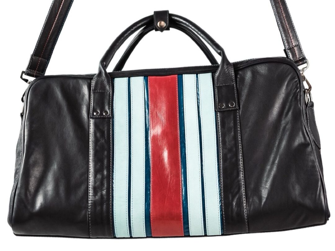 Introducing the Walter Leather Bespoke duffel bag, a luxurious accessory featuring sleek black leather with elegant blue, red, and white vertical stripes. It offers two short handles and a long adjustable shoulder strap for versatile carrying, blending function with custom style.