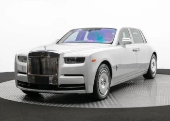 A silver Rolls-Royce Phantom Platino luxury sedan on display in a studio, featuring a prominent grille and sleek design.