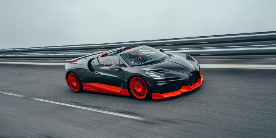 A sleek, black and red Bugatti W16 Mistral sports car speeds along a highway, with blurred motion emphasizing its world record-worthy fast movement.