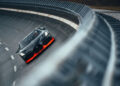 A sleek black and red Bugatti sports car, renowned for its world record speed, tears through a curved, banked track with barrier walls on both sides.