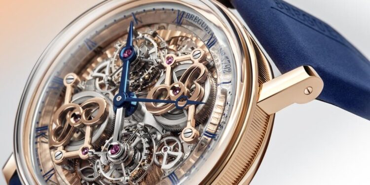 Close-up of a luxury watch from the 2024 collection, featuring a transparent skeleton dial with intricate mechanical details and blue hands, encased in gold, complemented by a stylish blue strap. Perfect for the discerning collector perusing the ultimate Luxury Watch Guide or duPont REGISTRY.