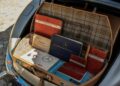 Open car trunk containing various vintage Mercedes-Benz manuals and documents, neatly organized in a patterned case, including rare items from the iconic 1957 Mercedes-Benz collection and insights on the legendary Rudge Roadster.