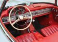 For sale: Immerse yourself in the timeless elegance of a 1957 Mercedes-Benz 300 SL. This vintage car interior boasts red leather seats and a silver dashboard, complemented by a classic steering wheel featuring the iconic Mercedes-Benz logo.