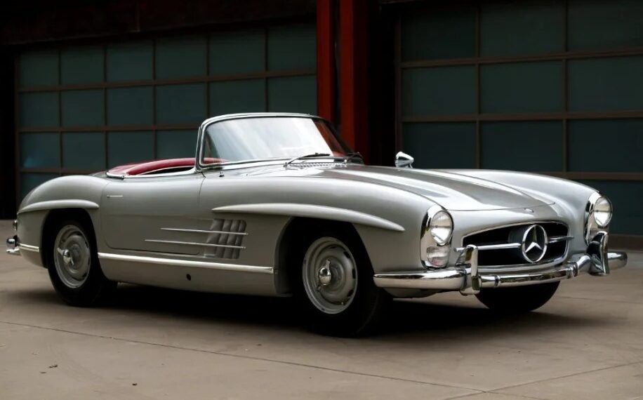 A classic 1957 Mercedes-Benz 300 SL convertible, a true Rudge Roadster, parked gracefully in front of a garage.