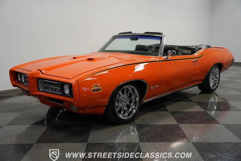 Orange classic convertible car with chrome wheels parked indoors, top down, showcasing its high-performance appeal. This timeless beauty is a prime example of classic muscle cars and is now for sale.