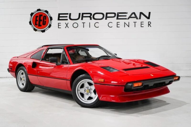 A red vintage sports car with a storied manual transmission is parked indoors at the European Exotic Center, with a logo visible on the wall behind it.