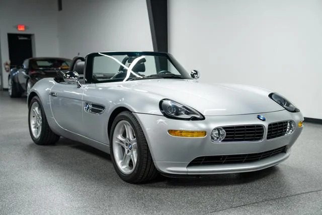 A silver BMW Z8 convertible, a modern classic, sits elegantly parked indoors on a gray floor.