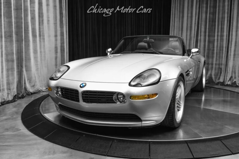 The sleek silver BMW Z8, an open-air modern classic, is displayed indoors with a "Chicago Motor Cars" banner in the background. This stunning automobile is now available for sale to those who appreciate timeless elegance and automotive artistry.