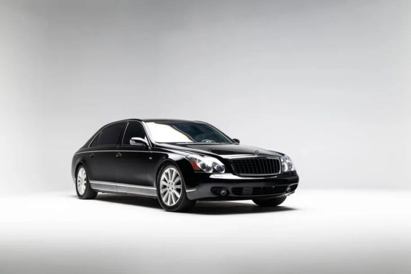 A black luxury sedan on a white background, evoking nostalgia with its sleek design and chrome accents reminiscent of the best 2000s cars.