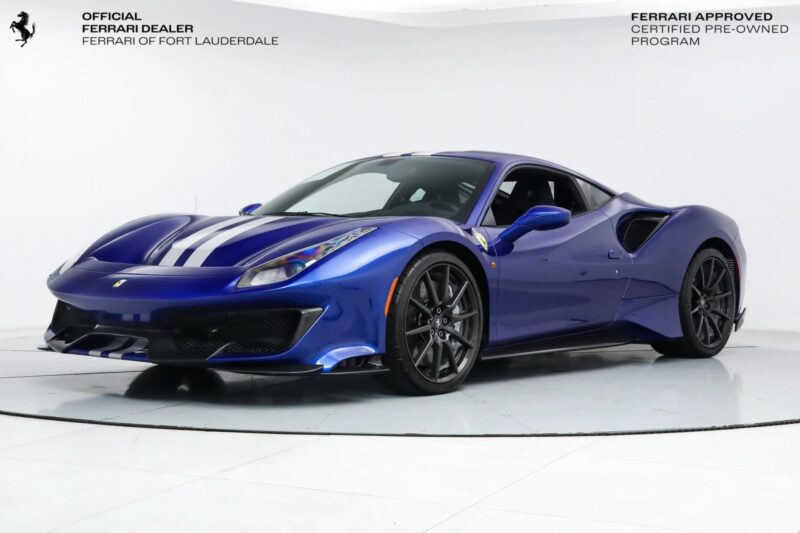 A blue Ferrari with white racing stripes is displayed in a showroom with white walls and floor, showcasing one of the striking Ferrari colors.