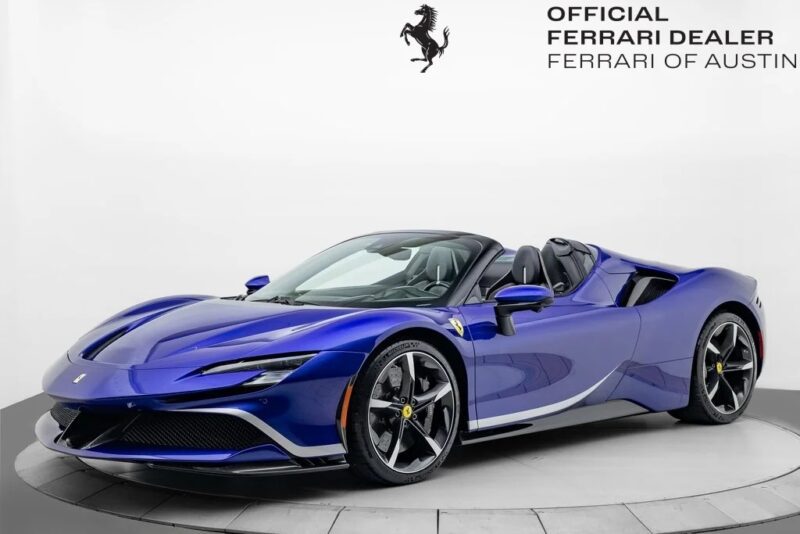 A blue Ferrari convertible in striking Ferrari colors is displayed in a showroom with "Official Ferrari Dealer Ferrari of Austin" branding on the wall, highlighting an exclusive Ferrari for sale.