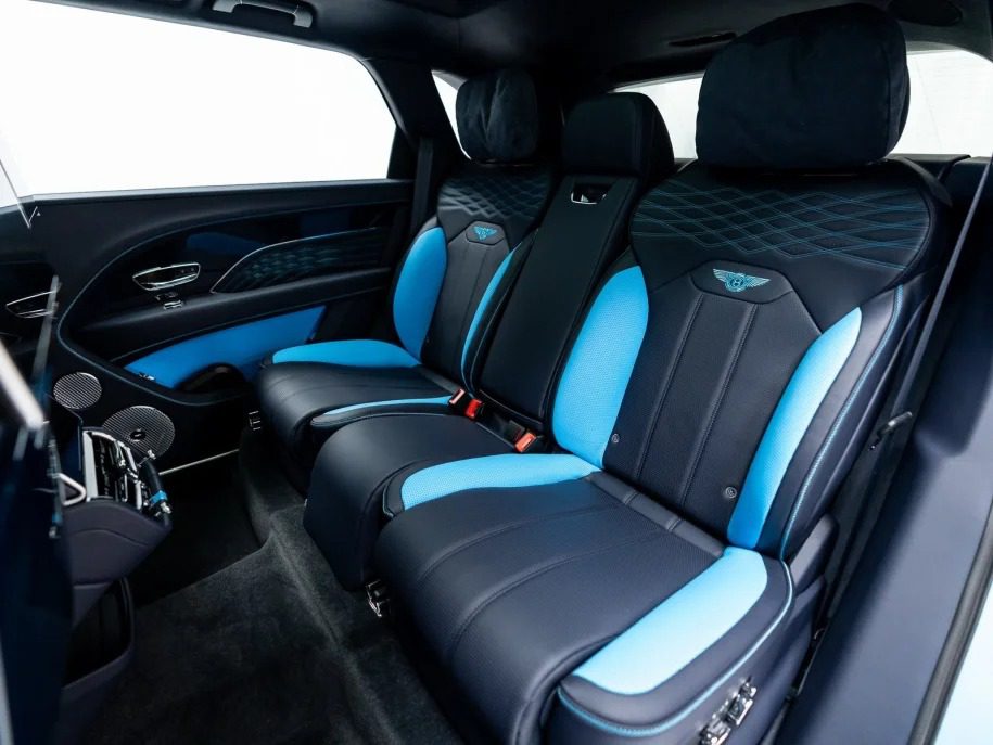 The interior of the ultra-luxe SUV showcases three black and blue leather seats with detailed stitching and an emblem on the headrests, exuding an air of sophistication akin to a Bentley Bentayga.