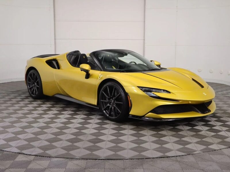 Yellow convertible Ferrari with black wheels displayed in a showroom featuring a checkered floor and plain white walls—showcasing one of the iconic Ferrari colors.