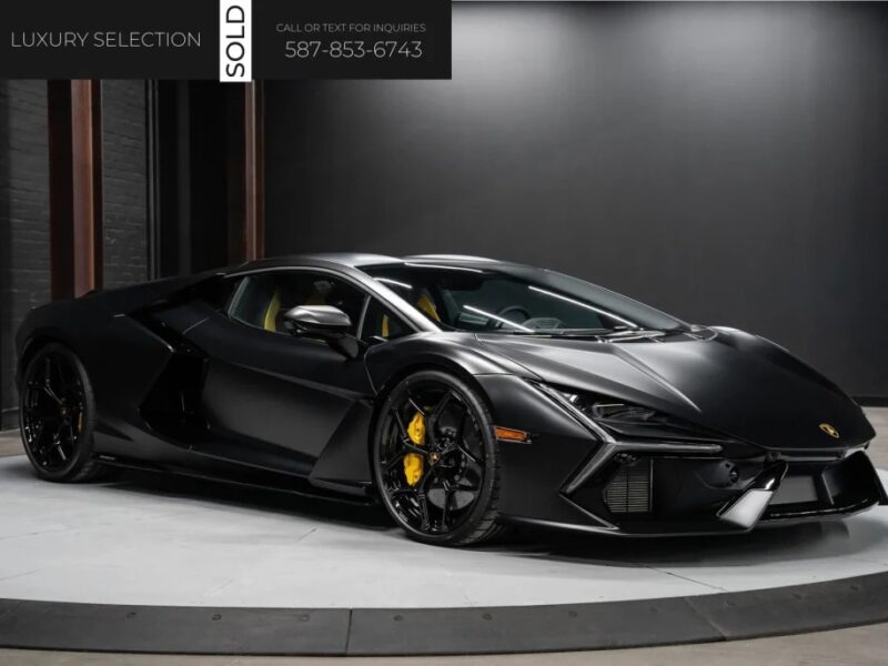 A black luxury sports car, the 2024 Lamborghini Revuelto, is showcased in a showroom. A "SOLD" sign is prominently displayed at the top left, with contact information available for those looking to buy a Lamborghini.