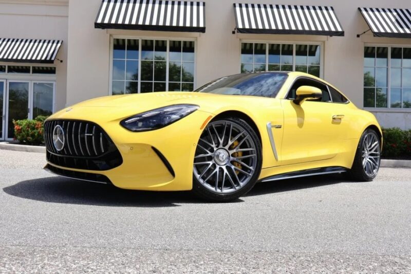A luxury yellow sports car is parked in front of a building with striped awnings, exuding an exotic charm.