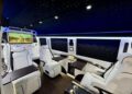 Experience the 2024 Ultimate Class inside this Jet Sprinter, featuring a luxurious van interior with white leather seats, LED lighting, a large TV screen, and a mesmerizing starry ceiling. This masterpiece by First Class Customs redefines comfort on the road.