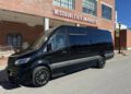 A black First Class Customs van parked in front of a Missouri State University building on a sunny day exudes an air of exclusivity, much like the 2024 Ultimate Class Jet Sprinter models.