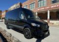 A sleek black Mercedes-Benz van, customized by First Class Customs, is parked in front of a building adorned with the "Missouri State University" sign.