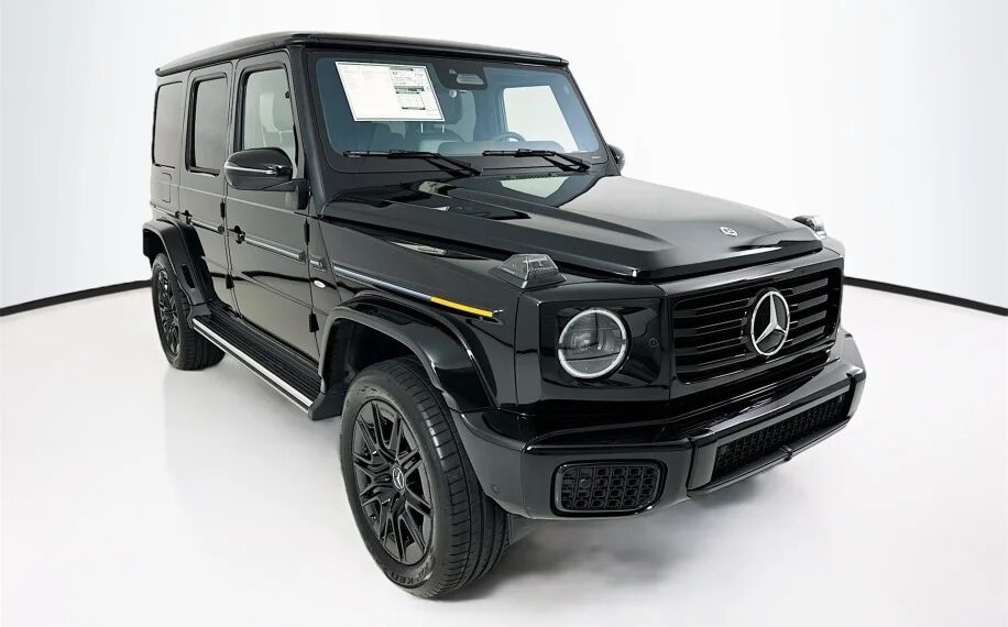 The sleek 2025 Black Electric Mercedes-Benz G-Wagon is showcased in a well-lit studio setting, exuding modern elegance. Now available for sale, this SUV combines cutting-edge technology with iconic design.