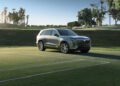 A silver Cadillac SUV is elegantly parked on a grassy field, framed by palm trees and a clear sky, showcasing the perfect blend of style and luxury.