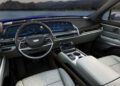 Interior view of a Cadillac Vistiq showcasing a modern car with a digital dashboard, sleek steering wheel, and light leather seating. A scenic landscape is visible through the windows, perfectly complementing the luxury EV experience.