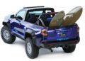 A blue Toyota TRD Surf truck, embodying Adventure Concepts, boasts an open cargo area with two surfboards. This rugged 2024 SEMA highlight is equipped with off-road tires, perfect for any terrain.