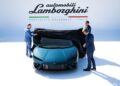 Three men proudly unveil a dazzling new model Lamborghini at an exclusive event, set against a backdrop featuring the iconic logo and location. The debut draws record numbers of enthusiasts eager to witness this remarkable moment in automotive history.