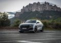 A silver Audi RS Q8 SUV is parked on a road with rocky mountains in the backdrop, embodying its superior performance and precision akin to an engineer's touch.