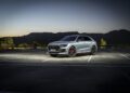 The Audi RS Q8, a masterpiece of chassis development and performance testing, sits majestically in an empty lot at dusk, with the serene mountains serving as its awe-inspiring backdrop.