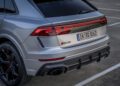 Rear view of a gray Audi RS Q8 parked in a lot, showcasing its sleek taillights, powerful exhaust, and license plate reading "IN RQ 8662." This model, refined by a skilled chassis developer, embodies the pinnacle of performance testing excellence.