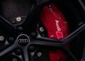 Close-up of a car wheel with a black rim, proudly displaying the Audi logo, and featuring a red brake caliper inside—a testament to the performance prowess of the Audi RS Q8.