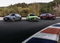 Three cars, including an Audi RS Q8 Performance in gray, green, and red, are parked on a racetrack with trees in the backdrop. The scene captures the meticulous work of the chassis developer amidst the vibrant landscape of Spain.