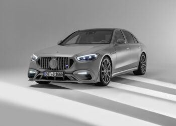 A BRABUS 1000 silver luxury sedan with bichromatic elegance, LED headlights, and a distinctive grille is parked in a well-lit studio setting.