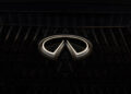 Close-up of the illuminated Infiniti logo on a dark vehicle grille, evoking the Tailgating Luxury vibe of the AUTOGRAPH Lounge series.