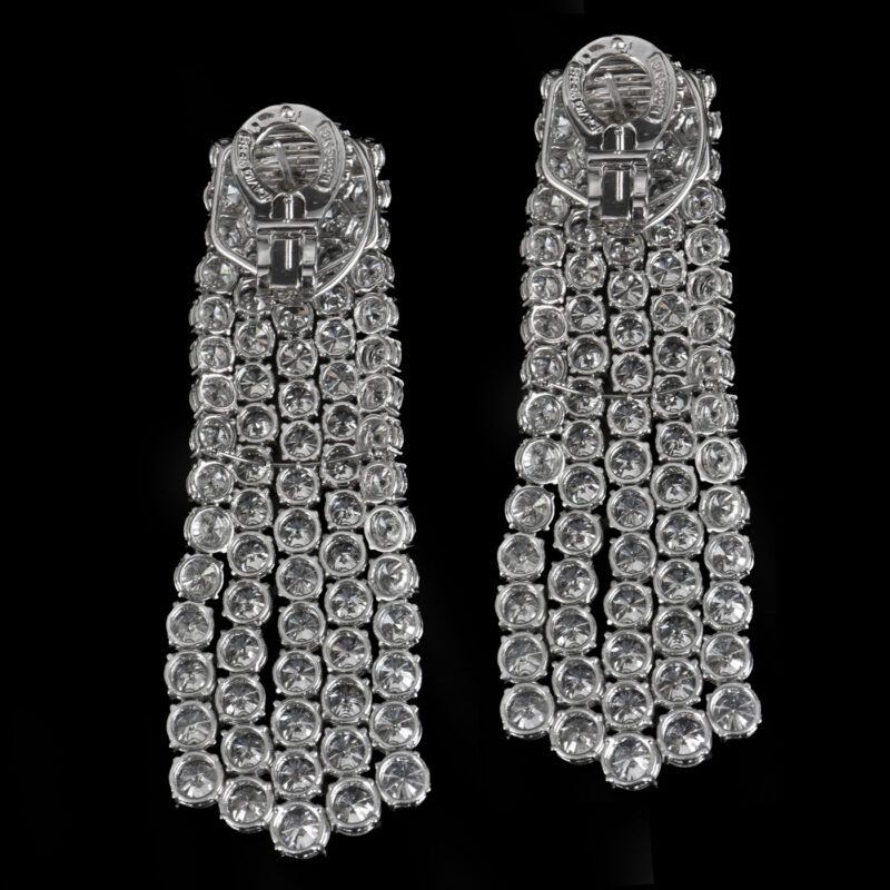 Two dazzling silver clip-on earrings with multiple rows of rhinestones create a sparkling effect against a black background, perfect for any jewelry enthusiast. These stunning pieces could easily be the highlight of any auction lineup.