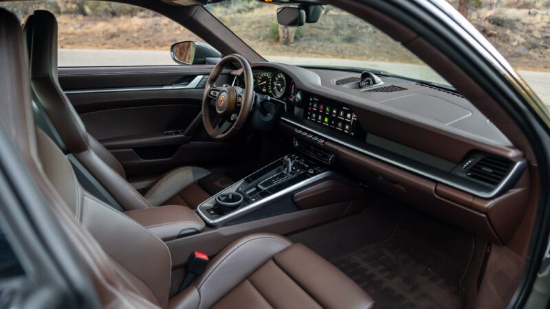 Interior of a luxury car with brown leather seats, sleek dashboard, and a central touchscreen display. Steering wheel on the left.