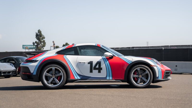 A sports car with a racing number "14" and colorful livery is parked on a sunny day.