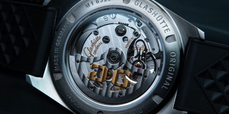 Close-up of the SeaQ Series watch's sapphire crystal case back, showcasing the intricate mechanical movement inside. The engravings and visible rotor are adorned with gold accents, a hallmark of Glashütte Original, standing out against a dark background.