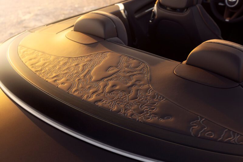 Close-up of a Bentley's interior, showcasing intricate leather detailing on the dashboard from the Bespoke Collection, with ambient lighting highlighting the texture.