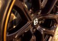 Close-up of a black Bentley wheel with a stylized "B" logo at the center, showcasing the bespoke spoke design and part of the brake disc.