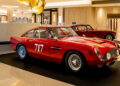 Two vintage red cars on display indoors, one in the foreground marked with "717" on the door, reminiscent of a classic speedster from an Aston Martin car collection in Las Vegas.