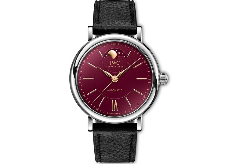 This luxury watch, featured in the duPont REGISTRY, boasts a burgundy dial, silver case, moon phase indicator, gold hour markers, and a black leather strap for an exquisite touch.