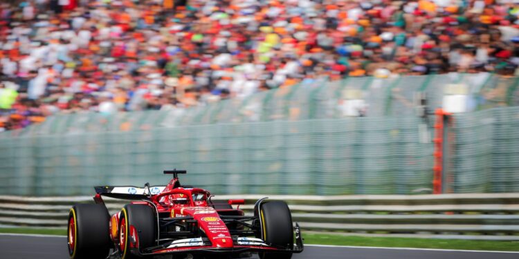 A red Formula 1 car surges from the starting grid, speeding along the track against the backdrop of a blurred crowd, embodying the thrill of the 2025 F1 Season.