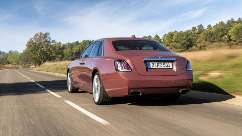 An image of a pink Rolls-Royce Ghost Series II on the road.