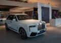 A white luxury SUV graces the modern showroom in Abu Dhabi, its sleek design elements and soft lighting perfectly highlighting the elegance of a Rolls-Royce.