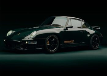 A dark green 993 Turbo by Porsche is parked in a dimly lit setting, showcasing a side and front view with glowing headlights, exuding an air of exclusivity reminiscent of Aimé Leon Dore's refined aesthetic.