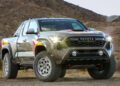 A rugged, off-road Toyota truck with large tires and a bold grille is parked on a dirt path in a desert landscape under the clear sky, embodying Adventure Concepts fit for the 2024 SEMA show.